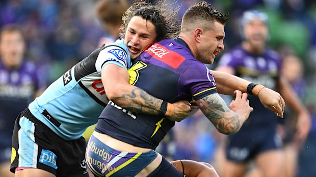Cameron Munster of the Storm is tackled Nicho Hynes of the Sharks.