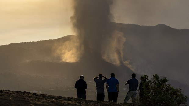 Residents watch from a hill as lava continues to flow from an erupted volcano, on the island of La Palma in the Canaries, Spain.