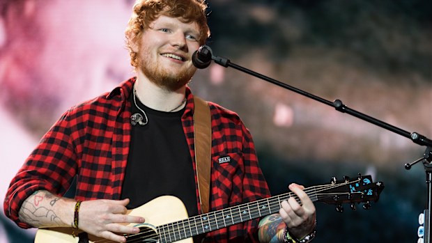 Ed Sheeran playing guitar with mic at concert 