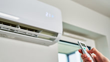 Hand adjusting temperature on air conditioner with remote control, Working air conditioner for comfort temperature in home at hot summer