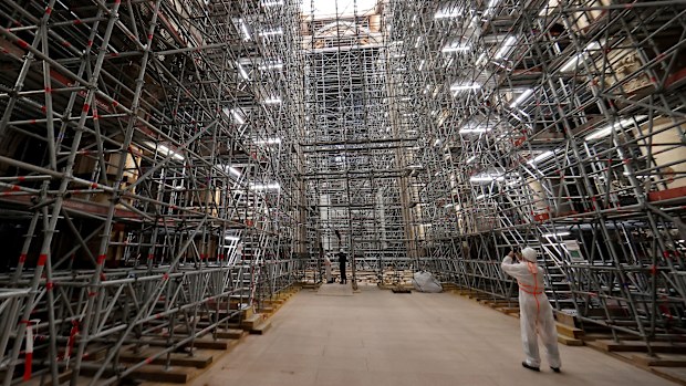 A worker takes a picture of the scaffolding's at the reconstruction site ahead a visit of the French president at the Notre-Dame de Paris Cathedral, in Paris, Friday, April 15, 2022.