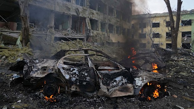 A car burns outside a maternity hospital damaged by shelling in Mariupol, Ukraine. 