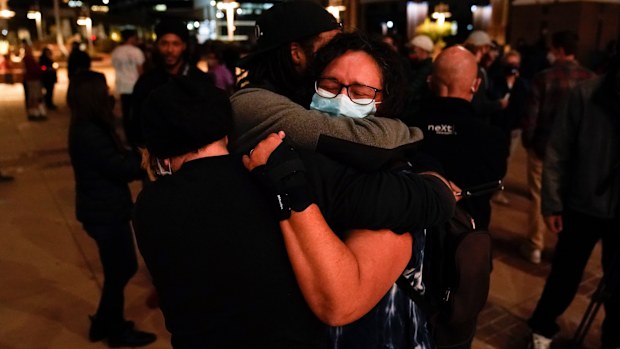 Three film industry workers comfort one another during the candlelight vigil. 
