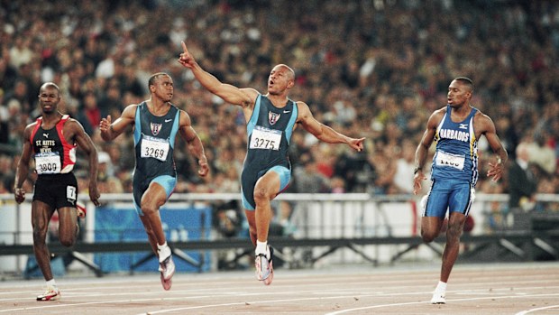 Maurice Greene celebrates winning gold in the 100m at the Sydney 2000 Olympics, ahead of silver medallist Ato Bolton (3269) and Obadele Thompson.
