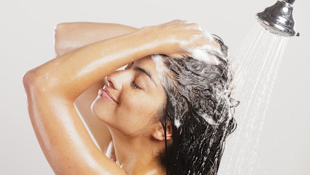 A dark-haired woman standing in a shower.