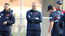 Michael Cheika looks on as Roosters coach Trent Robinson gives instructions to the players.