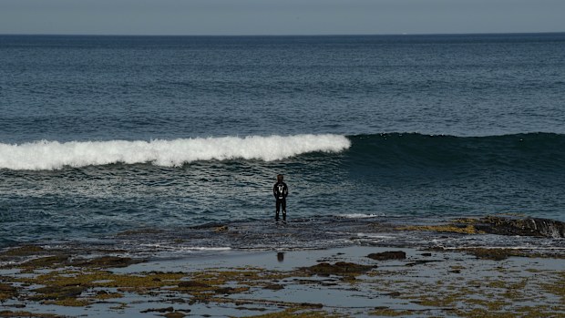 A boy stands on a reef at the waters edge near the ocean baths at Newcastle during the statewide COVID-19 lockdown. Newcastle, NSW. 10th September, 2021. Photo: Kate Geraghty