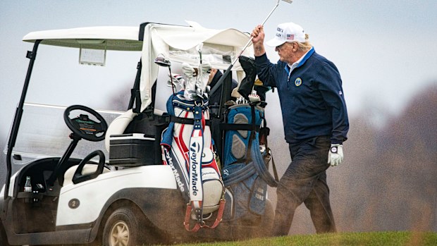 Donald Trump puts a club back in his bag after taking a shot.