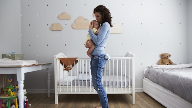 Mother Comforting Newborn Baby Son In Nursery