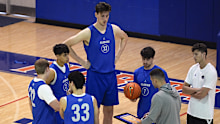 Olivier Rioux, back center, a 7-foot-9 NCAA college basketball player at Florida, gathers with coaches and teammates during a practice session.