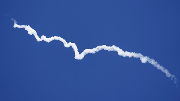 Blue Origin's New Shepard rocket leaves a smoke trail after lifting off.