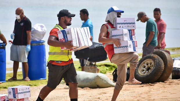 In this photo provided by Malau Media/IFRC, Tonga Red Cross Society's staff and volunteers unloading boxes of noodles from the boat into the beach in Nomuka on Ha'apai Island, Tonga on April 1, 2022. Three months on from a devastating volcano and tsunami in Tonga, the AP checks in on how the island nation is recovering. The bill from the tsunami is estimated at some $90 million and GDP is expected to fall by more than 7% this year. The cleanup has been hindered by an internet outage caused by th