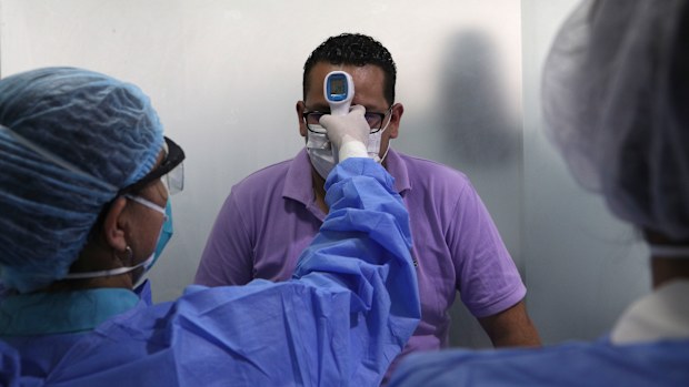 A man wearing a mask as a precautionary measure against the spread of the new coronavirus gets his temperature taken.