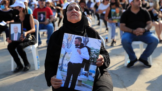 The mother of a victim who was killed in the massive blast last year at the Beirut port holds a portrait of her son as she attends a Mass held to commemorate the first year anniversary.