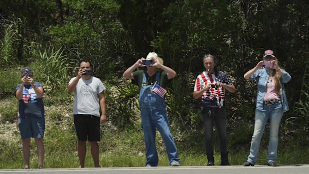 People watch as President Donald Trump and first lady Melania Trump pass in a motorcade in Kerrville, Texas, to monitor flood damage, Friday, July 11, 2025. (AP Photo/Jacquelyn Martin)