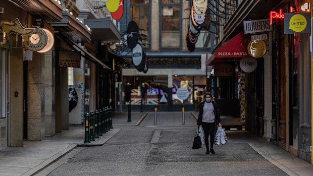 A lone shopper is seen carrying shopping bags as she walks down the usually busy Degraves Street laneway fame for its cafes and coffee as lockdown of Melbourne forces people to stay at home if not working due to the continuing spread of COVID-19. (Asanka Brendon Ratnayake)
