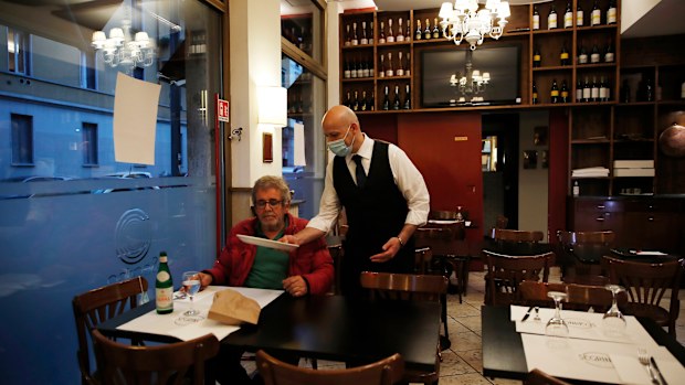 In this photo taken on Tuesday, May 19, 2020, a waiter tends to a customer at the "La Rotonda di Segrino" restaurant in Milan, Italy.