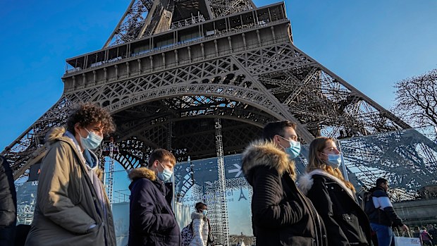 People wearing face masks to protect against COVID-19 walk past the Eiffel Tower in Paris, 
