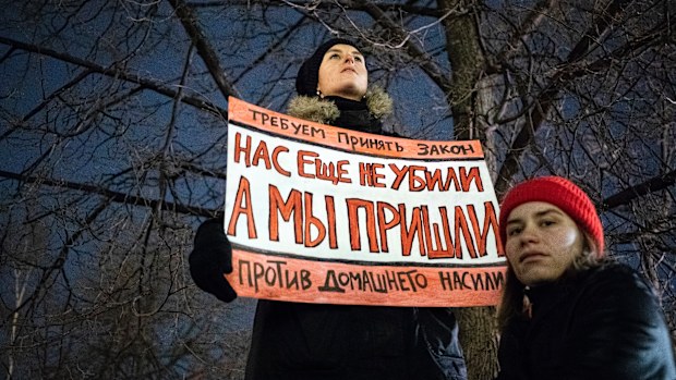 A woman holds a banner demanding Russia to change domestic violence laws. 