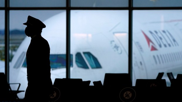 A Delta Airlines pilot wears a face mask to help prevent the spread of the new coronavirus as he walks through a terminal at Hartsfield-Jackson International Airport in Atlanta, Thursday, Feb. 18, 2021. (AP Photo/Charlie Riedel)