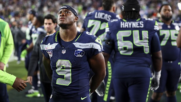 Kenneth Walker holding the Super Bowl MVP trophy after Seattle's victory, surrounded by celebrating teammates on the field at Levi's Stadium.