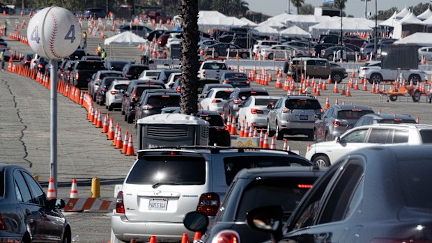 Cars wait in line as they enter a COVID-19 vaccination site at Dodger Stadium in Los Angeles.