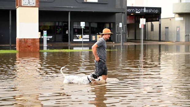 A man and his dog walk through floodwater on March 30, 2022 in Byron Bay, Australia. Evacuation orders have been issued for towns across the NSW Northern Rivers region, with flash flooding expected as heavy rainfall continues. It is the second major flood event for the region this month. (Photo by Dan Peled/Getty Images)