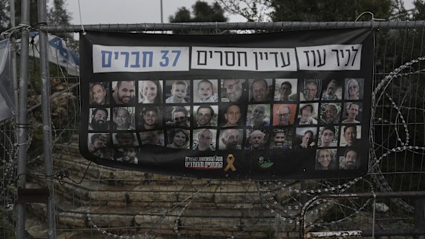 A poster shows portraits of Bibas family, top row from second left: Yarden, Shiri, and their sons Ariel and Kfir, who were kidnapped to Gaza on Oct. 7, 2023, in Jerusalem, Friday, Feb. 21, 2025. Letters on top read, "37 members of Kibbutz Nir Oz are still missing". (AP Photo/Mahmoud Illean)