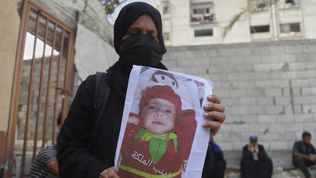 Esraa Abu Halib shows to journalists a photo of her 5-month-old baby, Zainab, who died from malnutrition-related causes, according to the family and the hospital, as she stands outside the Nasser Hospital, in Khan Younis, Gaza Strip, Saturday, July 26, 2025. (AP Photo/Mariam Dagga)