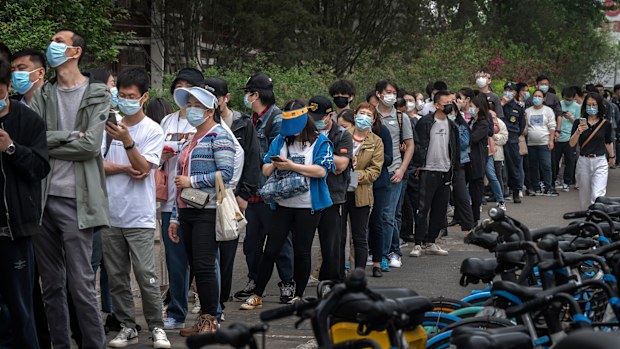 People line up for nucleic acid tests to detect COVID-19 at a makeshift testing site in Beijing's Chaoyang District. 