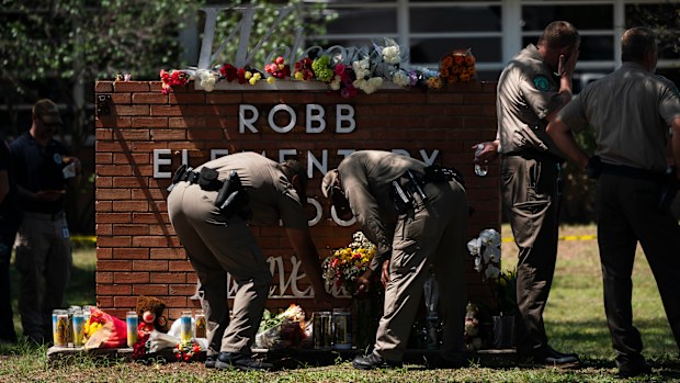 Two Texas Troopers light a candle at Robb Elementary School in Uvalde, Texas.