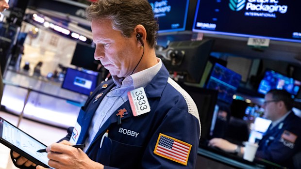 Trader Robert Charmak, left, works on the floor of the New York Stock Exchange.