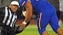 Football referee Fred Gracia falls to the ground after being charged by Emmanuel Duron.