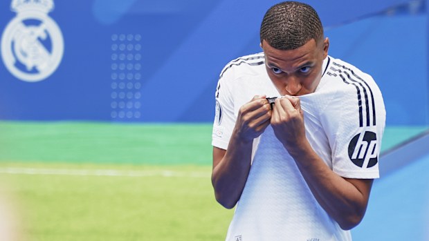 Kylian Mbappe kisses his new Real Madrid jersey during his presentation as a new Real Madrid player at Estadio Santiago Bernabeu.