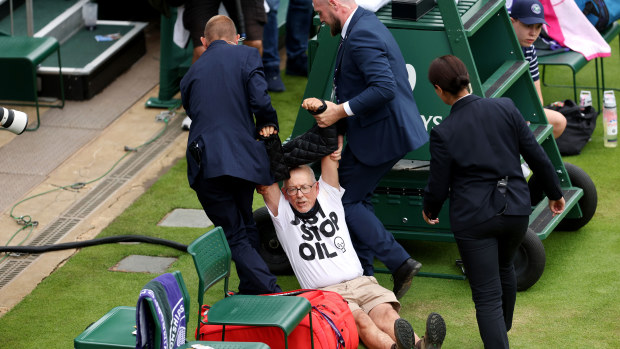 A protester is taken away by security on court 18 after a Just Stop Oil protest during the Women's Singles first round match between Katie Boulter of Great Britain and Daria Saville of Australia during day three of The Championships.