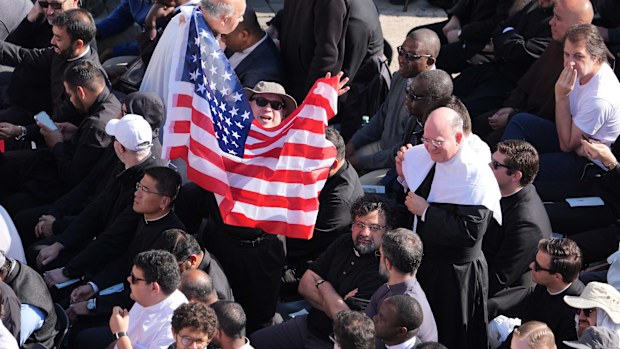 A man waves a US flag prior to the inaugural Mass of Pope Leo XIV.