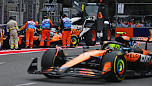 Marshals clear Oscar Piastri's car from the track as his McLaren teammate and championship rival, Lando Norris, drives by during the Azerbaijan Grand Prix.