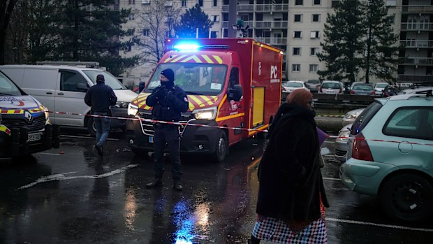 A police officer stands by a firefighter truck next to apartment buildings at Le Mas du Taureaum neighbourhood, in Vauls en Velin, outside Lyon, central France, Friday, Dec. 16, 2022.