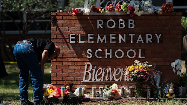 A law enforcement personnel lights a candle outside Robb Elementary School in Uvalde, Texas.