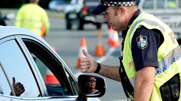 A motorist  is given the thumbs up by a police officer after being stopped at a checkpoint on the Gold Coast Highway at Coolangatta on the Queensland/NSW border,