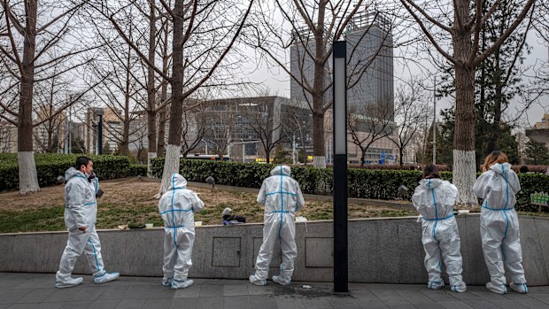 BEIJING, CHINA - MARCH 25: Health workers wear protective suits as they take a break to have dinner near a nucleic acid testing site for COVID-19 in the street on March 25, 2022 in Beijing, China. China has stepped up efforts to control a recent surge in coronavirus cases across the country, locking down the entire province of Jilin and the city of Shenyang and putting others like Shenzhen and Shanghai under restrictions. Local authorities across the country are mass testing as China tries to ma