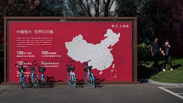 People walk by a map showing Evergrande development projects in China at an Evergrande new housing development in Beijing in September.