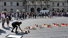 People pay a moment of silence on the main square after a former student opened fire the day before at a school fatally wounding several people and injuring many others before taking his own life, Graz, Austria, Wednesday, June 11, 2025 