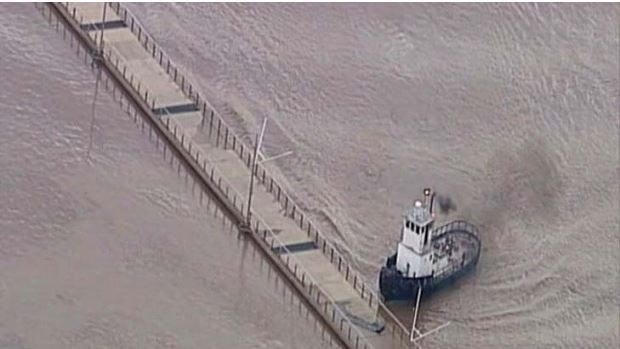 Peter Fenton's tugboat guides a 150-metre section of the floating Riverwalk out of harm's way during the Brisbane flood.