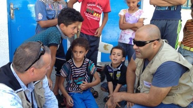 Mohammed Al Halabi, right, is seen talking to children in his work as Gaza program manager for World Vision.