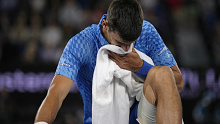 Novak Djokovic of Serbia reacts as he stretches his legs during his second round match against Enzo Couacaud of France at the Australian Open tennis championship in Melbourne, Australia, Thursday, Jan. 19, 2023. (AP Photo/Aaron Favila)