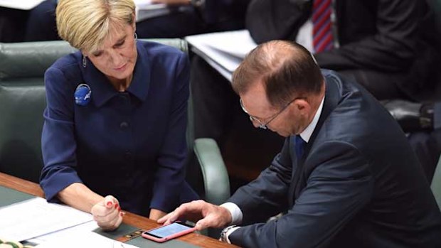 Prime Minister Tony Abbott and Foreign Affairs Minister Julie Bishop look at a mobile phone message during Question Time. (AAP)