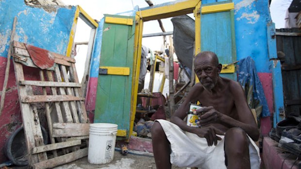 Jean Claude Dimanche in front of his ruined home. (AP)