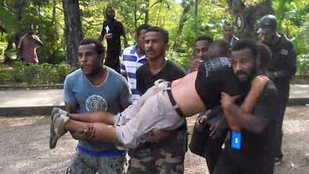 Protesters carry an injured protester who was shot by police during a march to Parliament in Port Moresby. (@Mangiwantok)