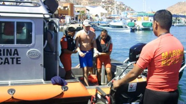 A passenger wearing a neck brace is helped off the tourist boat. 